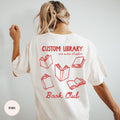 Woman wearing a white custom book club shirt with a red personalized library name, BOOK CLUB lettering and open-book back print.