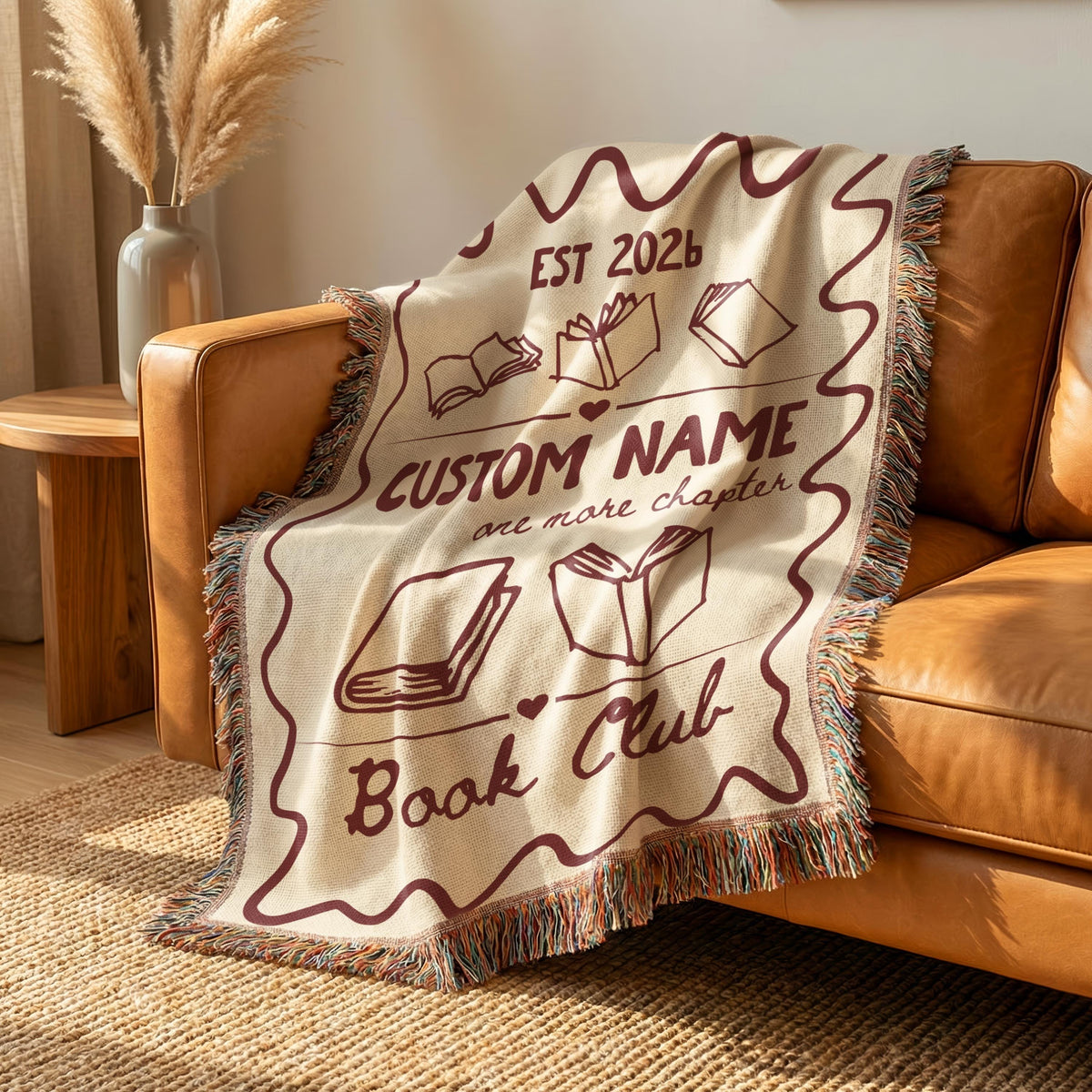 Close view of the personalized deep red book club design woven into a cream cotton blanket.